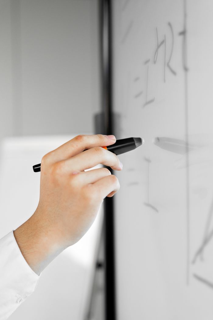 A professional writing with a stylus pen on a digital whiteboard in an office setting.
